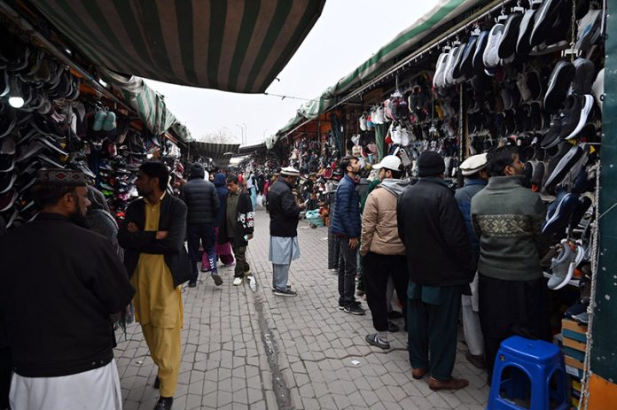 People select and purchase second-hand shoes from vendors at the weekly Sunday Bazaar at H-9 in the Federal Capital