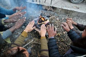 People are sitting around fire to keep themselves warm during cold weather in the Federal Capital