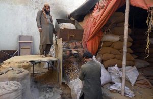 A worker busy in roasting the peanuts for customers at his workplace.
