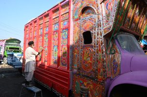 A painter applies intricate traditional designs while painting the body of a delivery truck at his workplace near Pirwadai