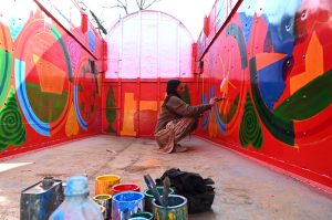 A painter applies intricate traditional designs while painting the body of a delivery truck at his workplace near Pirwadai