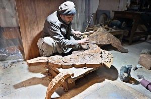 A carpenter busy in carving different designs on piece of wood at his workplace in Federal Capital.