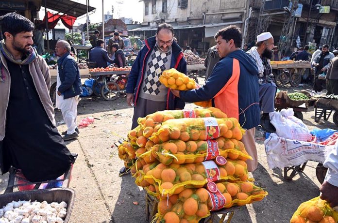 A vendor displays orange sacks for sale to attract customers at a fruit and vegetable market in the Federal Capital
