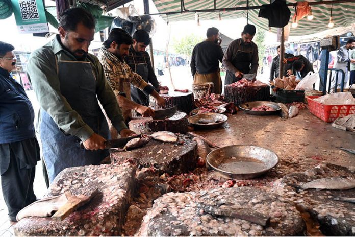 A vendor cuts and cleans fish for customers at H-9 Weekly Bazaar as demand for seafood rises during extreme cold weather in the federal capital