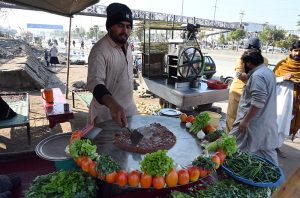 A vendor busy in roasting corn cobs at his roadside setup at Pirwadhai area