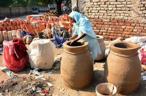An artisan woman prepares a traditional clay-made tandoor at her workplace.
