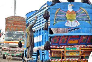 An artist decorates a truck with traditional truck art at his work place in twin cities.