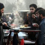 A street vendor serves traditional hot chicken soup with boiled eggs to customers to keep them warm during an extreme cold spell at a local market in the provincial capital