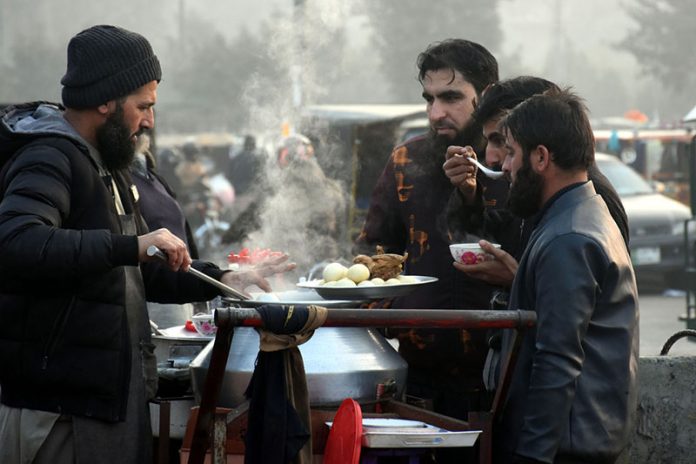 A street vendor serves traditional hot chicken soup with boiled eggs to customers to keep them warm during an extreme cold spell at a local market in the provincial capital
