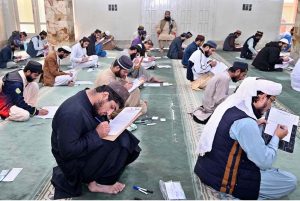 Madrasa students solving question paper during annual examination under the auspices of Wafaq Al-Madaris Al-Arabiya Pakistan at Jamia Ishatul Quran Wal Hadith Dodai Road.
