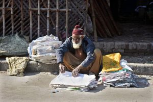 An elderly shopkeeper displays plastic bags at a local market.