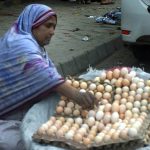 A female vendor displays eggs at her roadside setup, drawing customers with her welcoming demeanor