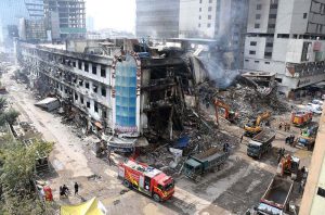 Rescue workers and firefighters use heavy machinery during search operation at the site of the burnt-out multi-story Gul Shopping Plaza following a massive fire.