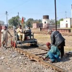 Railway staff inspect tracks using a manual push trolley during routine maintenance at the railway yard.