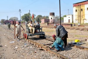 Railway staff inspect tracks using a manual push trolley during routine maintenance at the railway yard.