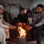 People sitting around a fire to keep warm amid cold weather