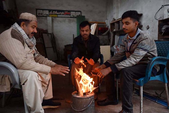 People sitting around a fire to keep warm amid cold weather