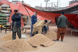 A distributor sells piles of groundnuts at a grain market to attract customers in the city
