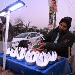 A street vendor sprinkles water on coconuts to keep them fresh and attract customers at a roadside in the federal capital