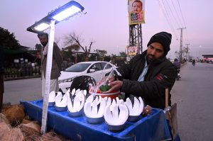 A street vendor sprinkles water on coconuts to keep them fresh and attract customers at a roadside in the federal capital