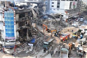 Rescue workers and firefighters use heavy machinery during search operation at the site of the burnt-out multi-story Gul Shopping Plaza following a massive fire.