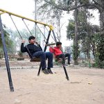 Youngsters enjoy swings at a local park in the city
