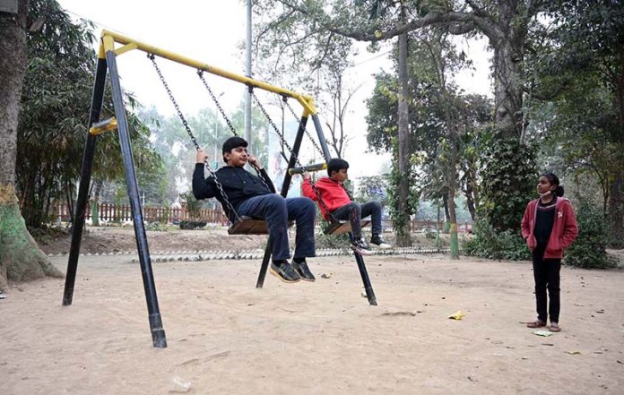 Youngsters enjoy swings at a local park in the city