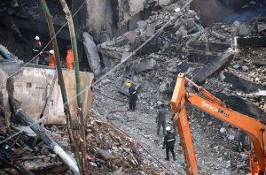 Rescue workers and firefighters use heavy machinery during search operation at the site of the burnt-out multi-story Gul Shopping Plaza following a massive fire.