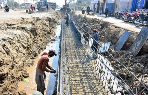 Labourers busy in construction work of sewerage line at autobahn road during development work in the city.