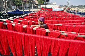 A worker busy spreading colorful thread for drying purpose after preparing at local factory.