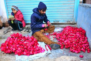 A worker busy in preparing flowers garlands for selling at his workplace.