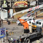 A HESCO worker works atop an electric pole, repairing a damaged cable to restore power supply in the Saddar area