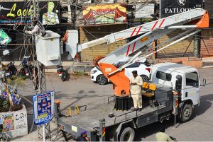 A HESCO worker works atop an electric pole, repairing a damaged cable to restore power supply in the Saddar area