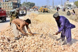 Labourers busy in construction work of sewerage line at autobahn road during development work in the city.