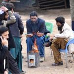 People are sitting around fire to keep themselves warm during cold weather in the Federal Capital