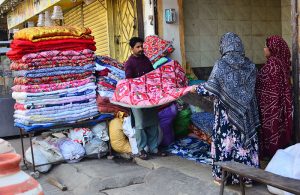 Women are busy selecting and purchasing quilts from a vendor during the chilly winter weather in the city.