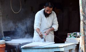 A worker busy in cutting the stone with help of cutting machine at his workplace.