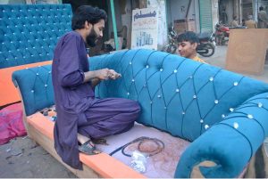 Workers are busy making a sofa at their roadside workshop.