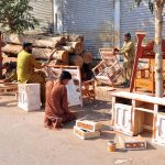 Carpenters apply primer to furniture before polishing at his workplace in the city
