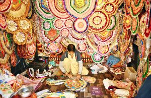 A worker is busy preparing a money necklace at his workplace during the wedding season.