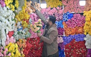 A shopkeeper arranges artificial flowers at his shop to attract customers, as demand remains high among event management companies in the Bhanni area of the twin cities.