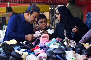 Women selecting and purchasing old warm clothes from vendor during winter season.