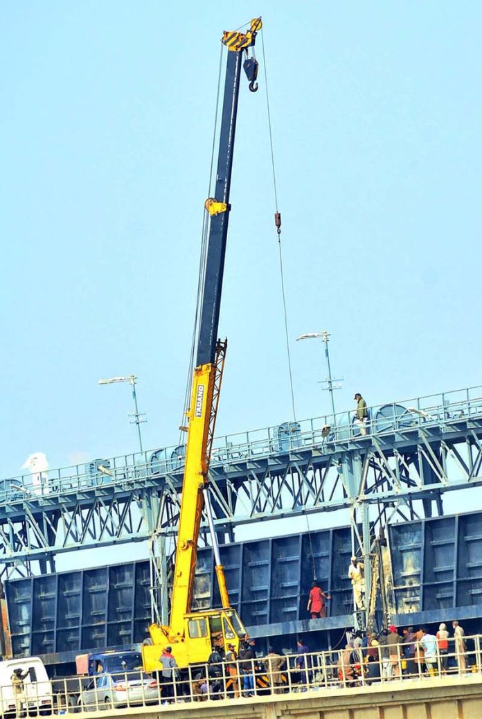 Workers of Irrigation department busy repairing and cleanup the Kotri Barrage Bridge doors with help of heavy machines at Indus River, Jamshoro