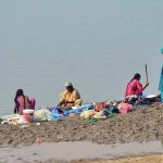 Gypsy women are busy washing clothes at the bank of Indus River.