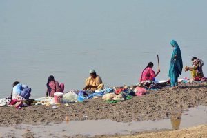 Gypsy women are busy washing clothes at the bank of Indus River.