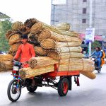 A tricycle rickshaw driver transports a bundle of cane stick curtain loaded on his rickshaw along Jail Road.