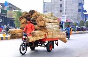 A tricycle rickshaw driver transports a bundle of cane stick curtain loaded on his rickshaw along Jail Road.
