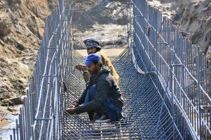 Labourers busy in construction work of sewerage pipe line with help of heavy machine at autobahn road during development work in the city.