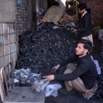 A coal vendor packs coal into plastic bags for customers as demand rises due to dropping temperatures in the city.