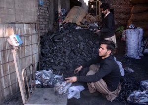 A coal vendor packs coal into plastic bags for customers as demand rises due to dropping temperatures in the city.